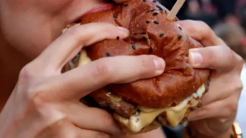 EPA Close up of a cheeseburger being eaten outside