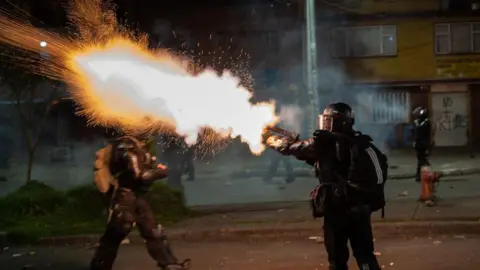 Getty Images A police officer seen firing tear gas into a crowd of protesters during anti government demonstrations in 2021