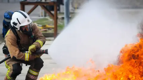 A firefighter battling a fire with a hose - generic