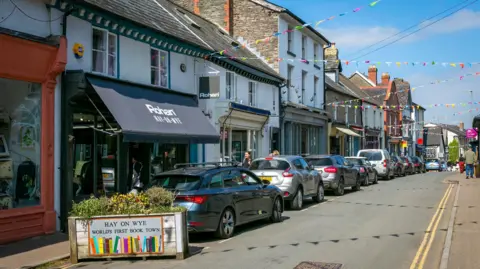 Getty Images A town's street with ribbons tied across it at roof-level. A sign reads "Hay on Wye, world's first book town".