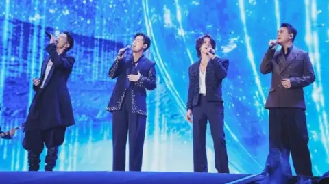 (From left) Vanness Wu, Vic Chou, Jerry Yan and Ken Chu, in black/gray suits and long pants, singing their hit ballad Meteor Rain at the Taipei Arena