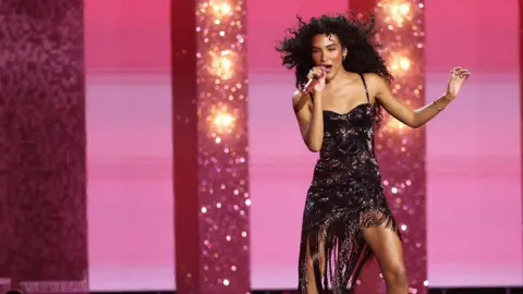 EPA/Shutterstock Olivia Dean performing at the Brits for fans while wearing a black dress