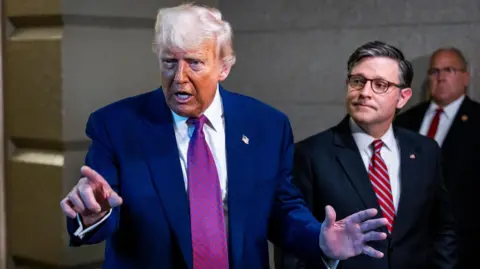 Trump pointing and gesturing as Johnson beside him looks at the president