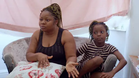 Mother Jane sits on sofa next to one of her children