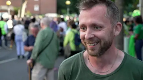 Peter Apps wears a green T-shirt on a busy street