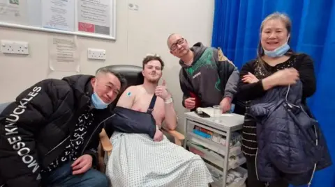 Jack Whincup, seated second from left, with a hospital gown wrapped around him, with friends, who he says look after him like family: Ronald, Seuky and Aman