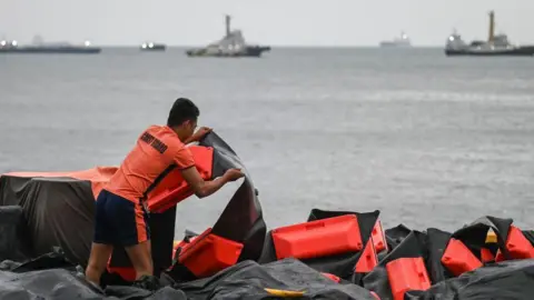 Getty Images A coast guard personnel arranges an oil spill containment boom to be on standby for deployment in the Philippines. 