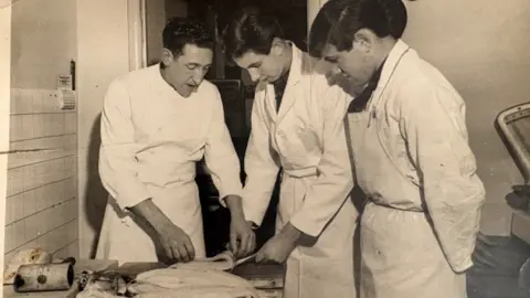 The Fisheries, Melksham An old photo of men in white aprons cutting a fish.