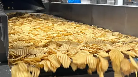 Abigail Jaiyeola/BBC A photo of crisps being moved along a production line inside the Seabrook factory.