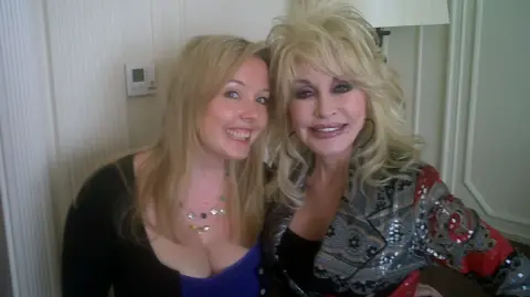 Smiling blonde Jade Wright, former music editor of the Liverpool Echo, smiles next to Dolly Parton, wearing a sequinned grey jacket