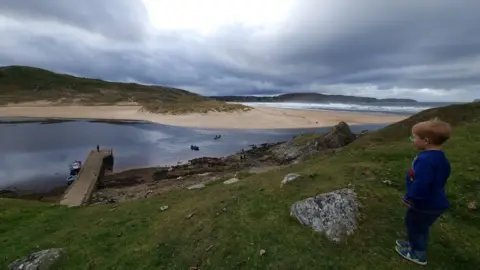 Strathnaver Museum A boy dressed in blue looks down on Bettyhill pier 