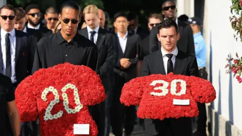 Liverpool players Virgil van Dijk (C) and Andy Robertson (R) carry floral tributes 