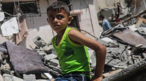 A Palestinian boy sits on rubble in Nuseirat refugee camp