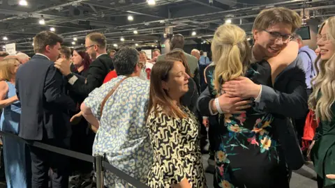 A crowd of people at a count are hugging and cheering