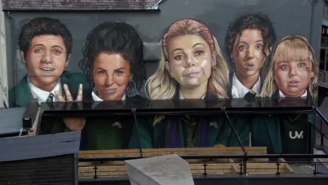 BBC Derry Girls mural showing the characters on a gable wall with awning blocking the view of the bottom half