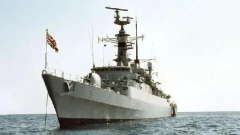 HMS Ambuscade sailing on water with flag raised
