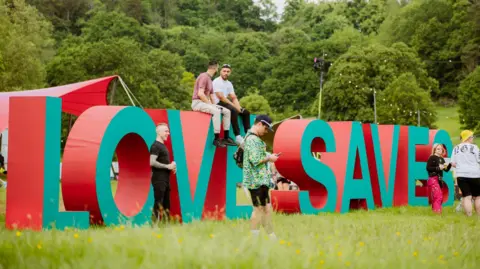 People sitting on top of a giant Love Saves lettering