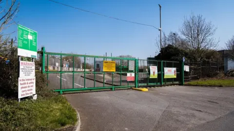 Industrial gates across a road leading into a larger industrial area