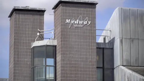The image shows the outside of a council building, with a silver sign that reads Medway Council.