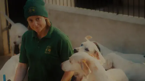 Mary Perry Mary Perry in a green woolly hat and green polo shirt is surrounded by the hunts hounds