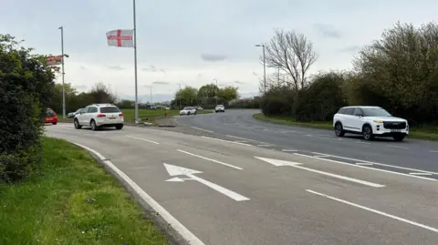 Stuart Woodward A roundabout at Canvey Island, with two lanes of traffic approaching it and other vehicles already on the roundabout. The left-hand lane shows a painted arrow which instructs motorists to turn left or go straight on, whilst the right-hand lane tells motorists to go straight on