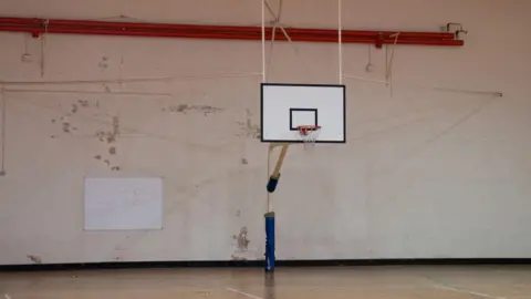 PA Media A basketball court at MDP Wethersfield with a tatty wall and a whiteboard.