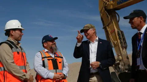 Reuters Chilean President Jose Antonio Kast points as he speaks to construction workers beside a digger.
