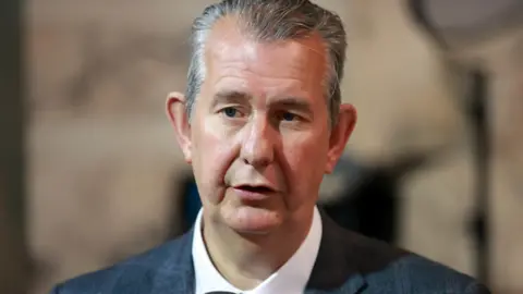 PA Media A man with dark, greying hair, is looking to the left of the camera He is wearing a suit with a white shirt and is only visible from the shoulders up. Behind him is a blurred background. 