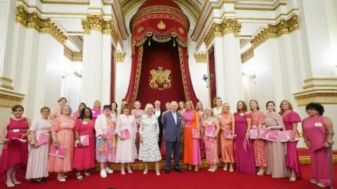 Ian Jones Photography/ Alamy The Check and Change choir members with King Charles III and Queen Camilla at Buckingham Palace. The members are holding pink folders branded with the Lorraine's programme name.