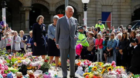 Reuters King Charles stands next to the tributes in front of the town hall in Southport on the day of his community visit