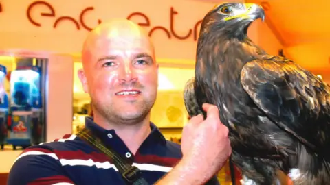 A man in a blue red and white striped shirt holding an eagle