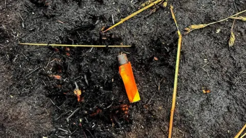 Market Drayton Fire Station An orange lighter left on blackened, burnt ground