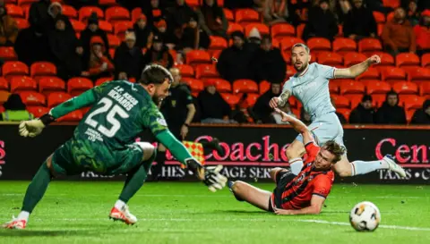 SNS A goalkeeper reaches for the ball watched on by a Dundee United player and Motherwell player