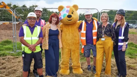 Pudsey the Bear and DIY SOS members with Julie on a building site
