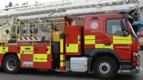 A red fire engine with yellow checks and Tyne and Wear Fire and Rescue Service branding