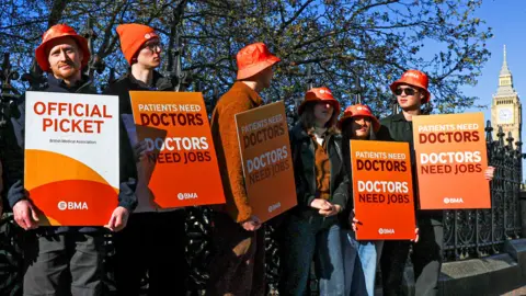 Resident doctors hold placards during a picket on the first day of a six-day industrial action after rejecting the government’s 3.5% pay increase, amid a dispute over pay and staffing pressures, in London, Britain, April 7, 2026.