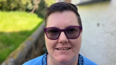 Woman wearing reactolite glasses smiling at the camera. She has short black hair