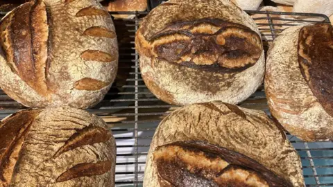 Alexander Taylor Sourdough loaves of bread on a wire rack.