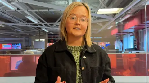 Catherine Moore has blonde hair and glasses.