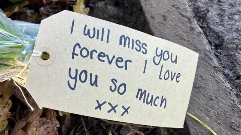 Nicola Rees/BBC Note attached to floral tribute which reads "I will miss you forever I Iove you so much xxx"