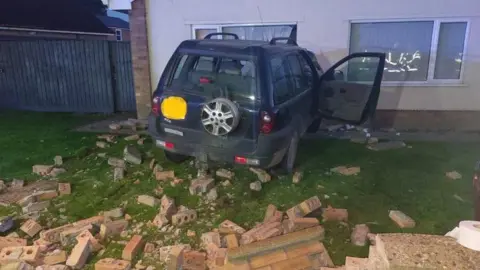 Crashed car and demolished wall