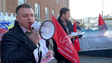 A Unite union member uses a megaphone at a protest event outside the council house in Derby. 