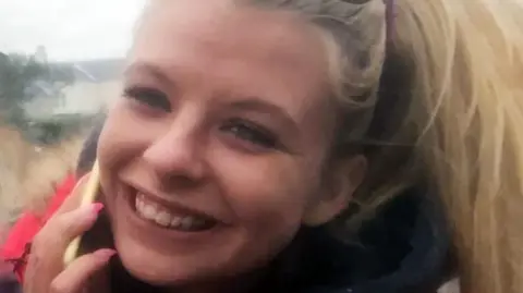 Police Scotland A young woman with blonde hair and a mobile phone held to her right ear smiles at the camera