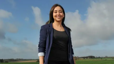 RAU A photo showing Dr Karen Rial Lovera from The Royal Agricultural University stood outside with blue sky and clouds in the background