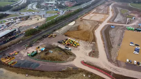 Qays Najm/BBC An aerial picture of how the site looked when it was undeveloped. It is covered in dirt and mud, with a series of diggers and trailers parked on it.