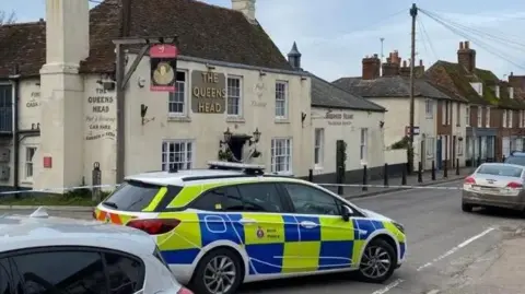 A police car and tape in front of The Queens Head pub in Boughton-under-Blean.