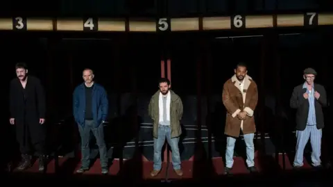 Jason Roberts Five man lined up on stage under dole queue numbers for the stage production of Boys From The Blackstuff at Liverpool's Royal Court