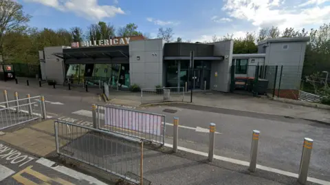 Google The entrance to Billericay Rail Station. The sky is blue and the road outside is visible. 