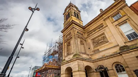 The light coloured stone of the Guildhall Theatre building with scaffolding over part of it