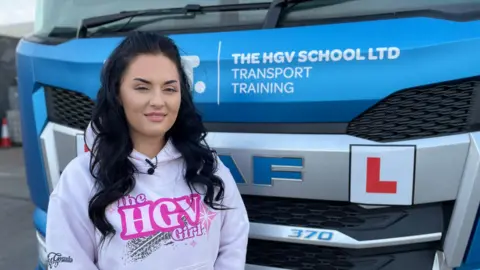 Shannan Paterson, sales and operations coordinator of the HGV School in Willenhall, stands in front of one of their HGVs which is used for training